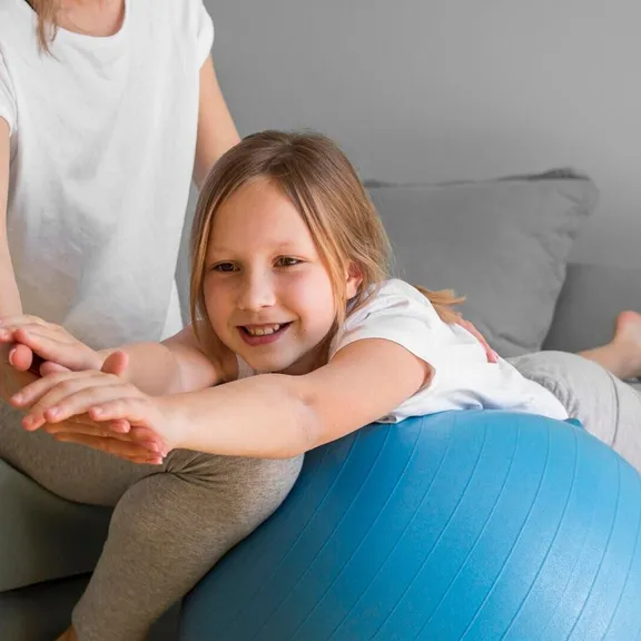 Mom helping girl to exercise on ball