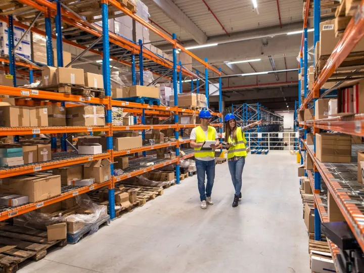 Two warehouse workers walking in distribution storage area d