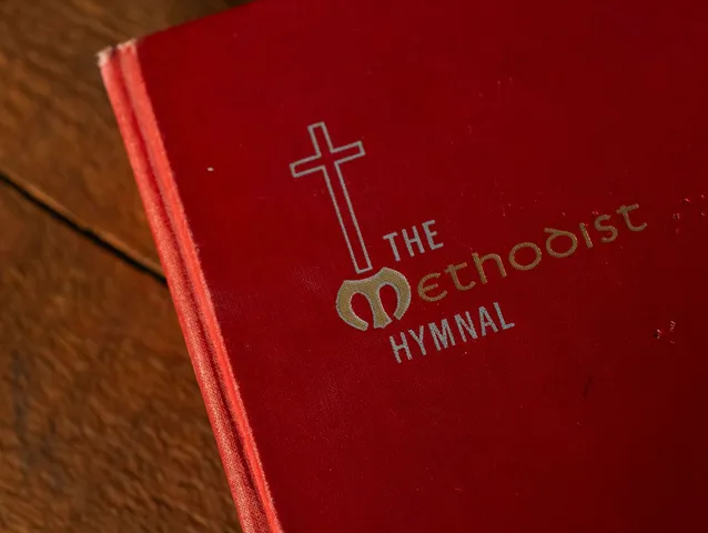 A Methodist hymn book resting on a wooden table