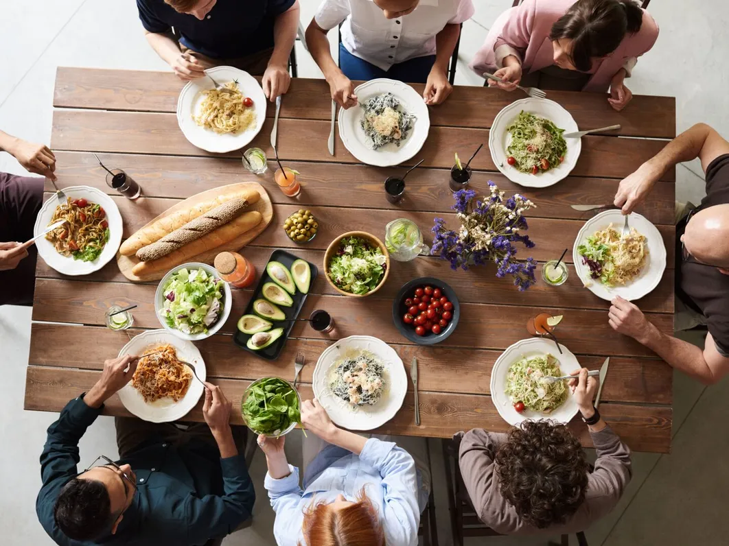 A diverse group sharing a meal together around a long table