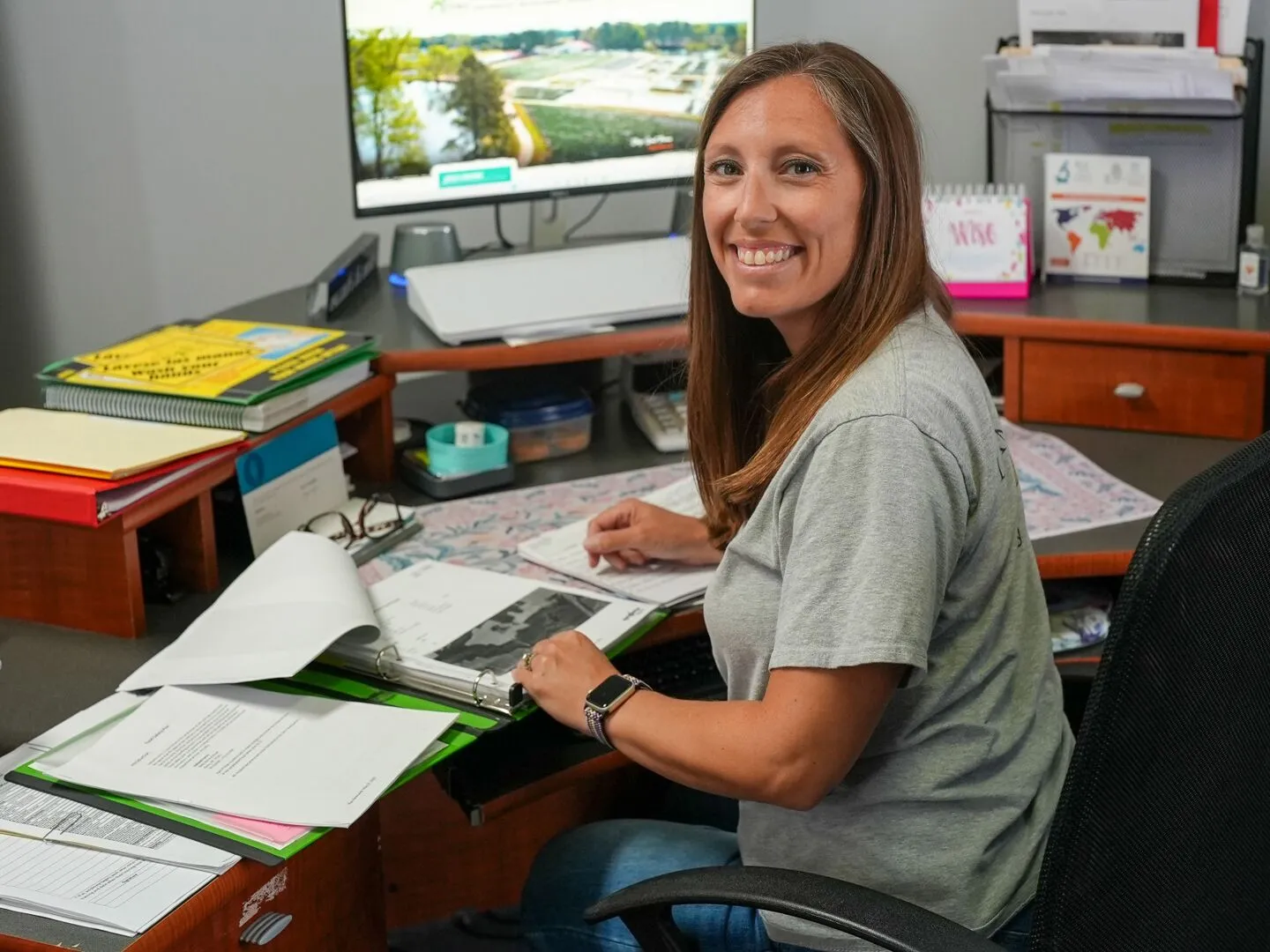 Smiling nursery manager reviewing a policy folder at an office desk