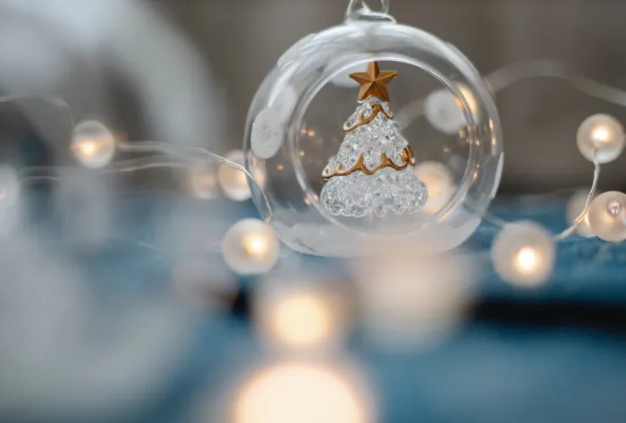 Glass Christmas tree inside transparent ball surrounded by burning garland for festive decorations