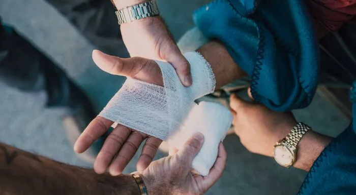 Person Applying Bandage on Another Person's Hand
