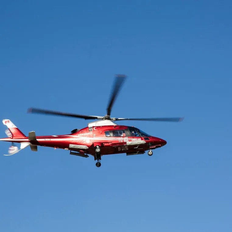 Red helicopter flying against clear blue sky, symbolizing emergency medical rescue.