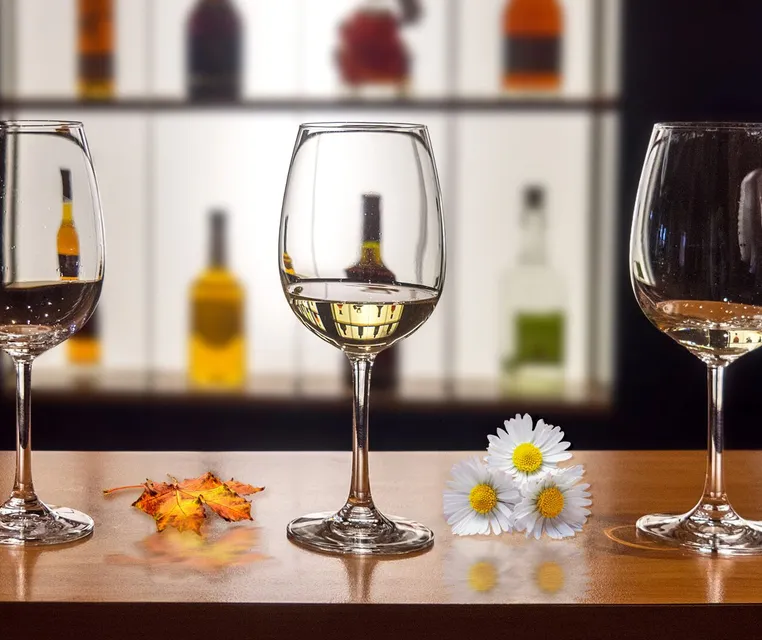 Wine glasses on a table with daisies