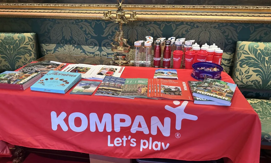 Kompan exhibition stand with brochures on a red table cover