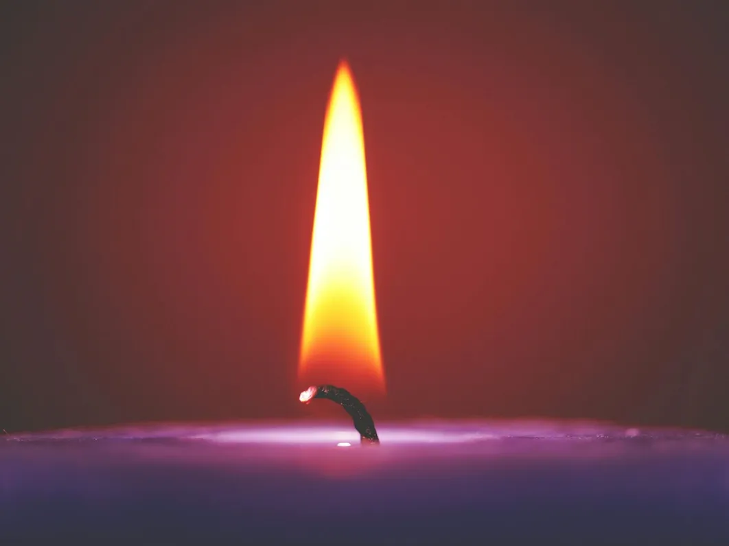 Close-up of a glowing candle flame against a dark