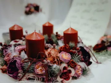 Warm, festive candle wreath adorned with floral decorations, perfect for Christmas table settings.