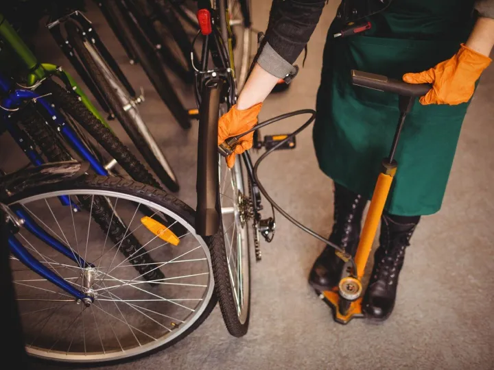 Mechanic filling air into bicycle tire with air pump