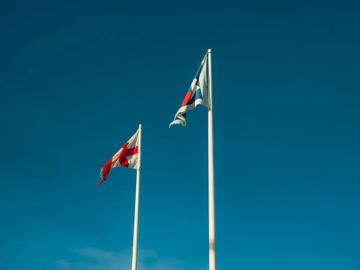 Two flags on poles against a clear blue sky