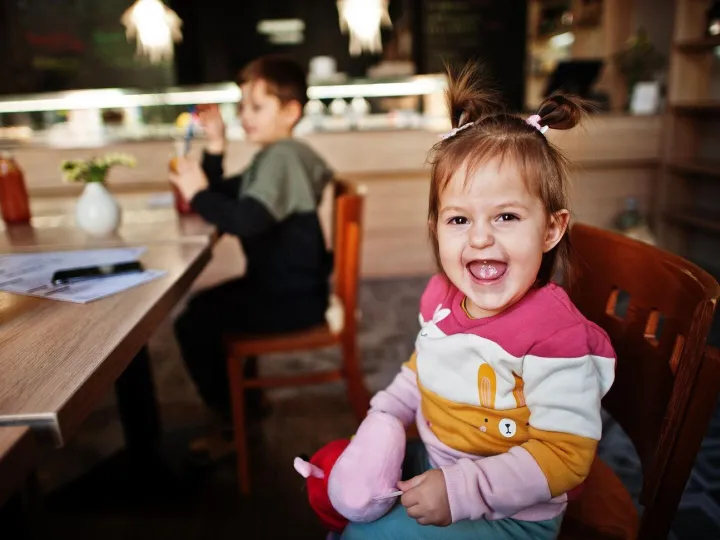 Funny baby girl sitting in cafe and laughs