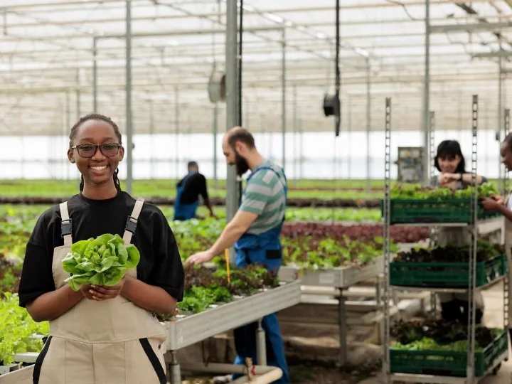 Happy cheerful african american farm worker holding ripe org