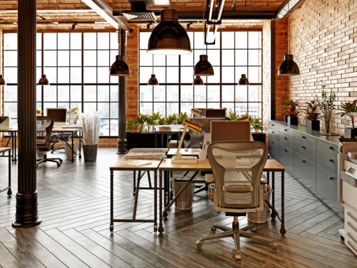 Open plan office with large windows and brick wall