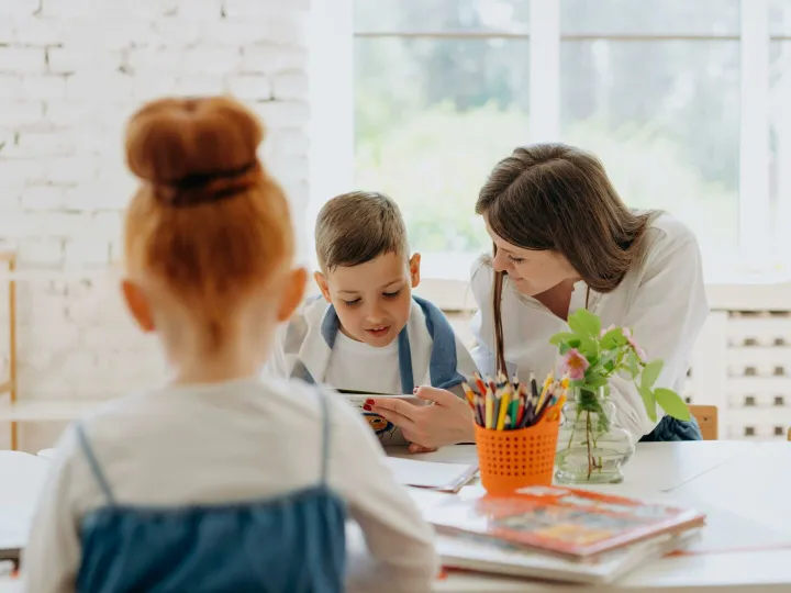 Engaging learning experience with a teacher and child exploring books and creativity in a bright classroom.