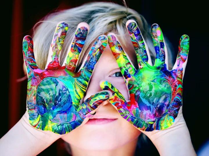 Vibrant close-up of a child's hands covered in colorful paint, expressing creativity and fun.