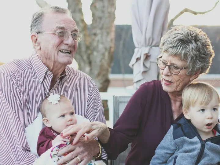 Grandparents spending joyful moments with their grandchildren in an outdoor setting, captured candidly.