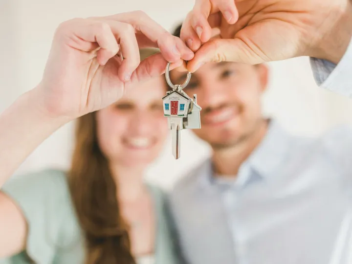 Young couple holding keys to their new home, symbolizing a fresh start and investment in real estate.