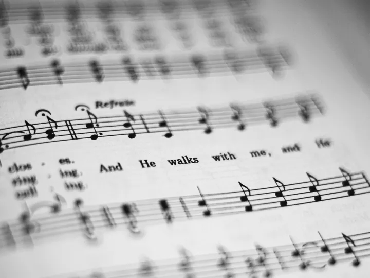 Close-up of black and white sheet music featuring musical notes and lyrics in focus.
