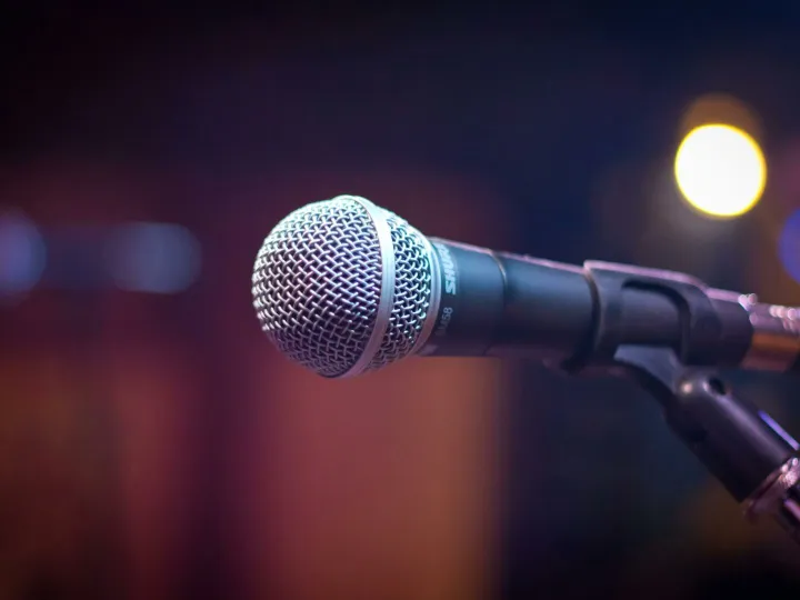 Dynamic microphone on stand with blurred stage lights in background.