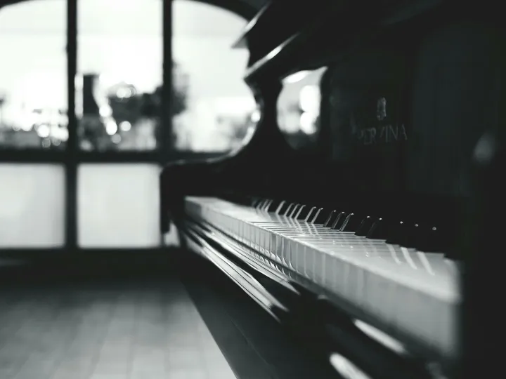 Stylish black and white close-up of a piano inside a room with soft lighting.