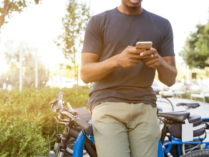 Casual young man leaning on a bike outdoors while