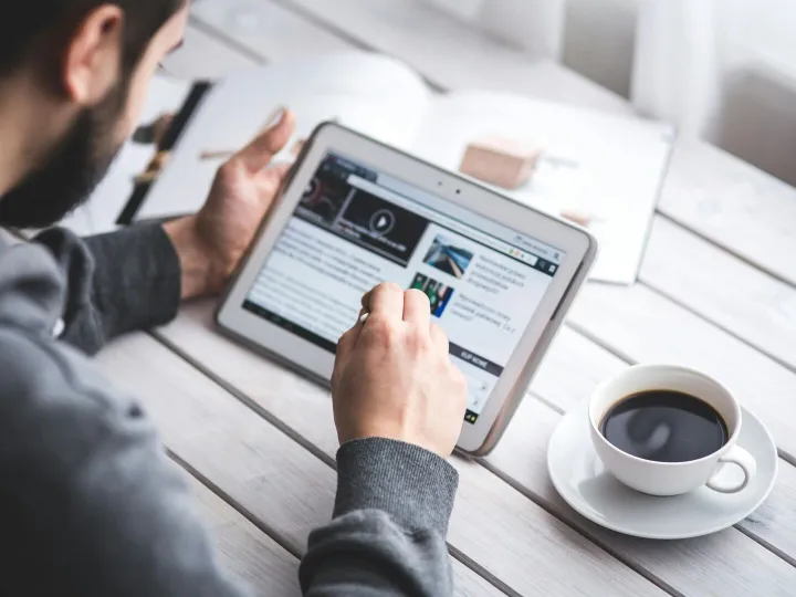 A man uses a tablet to browse news while enjoying