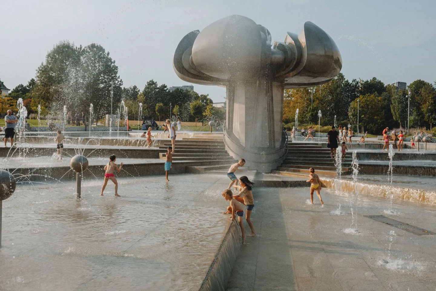 Children playing in an outdoor water fountain on a sunny day