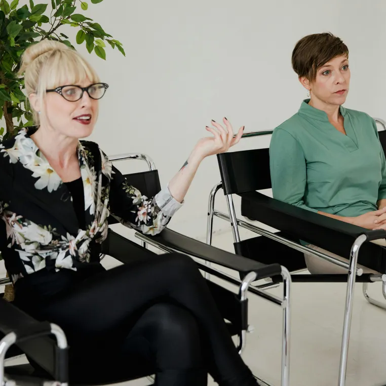 Women Sitting on Chairs in a Modern Interior and One Woman Talking