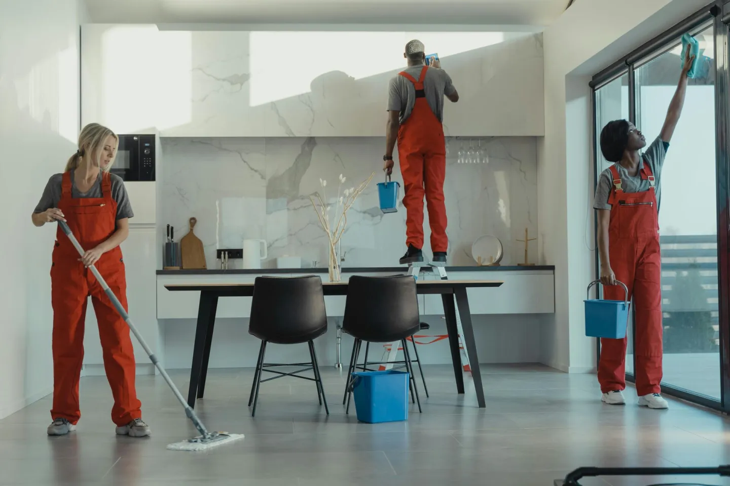 Group of cleaners in red uniforms mopping and