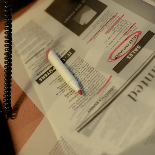 Close-up of a newspaper job section with a red