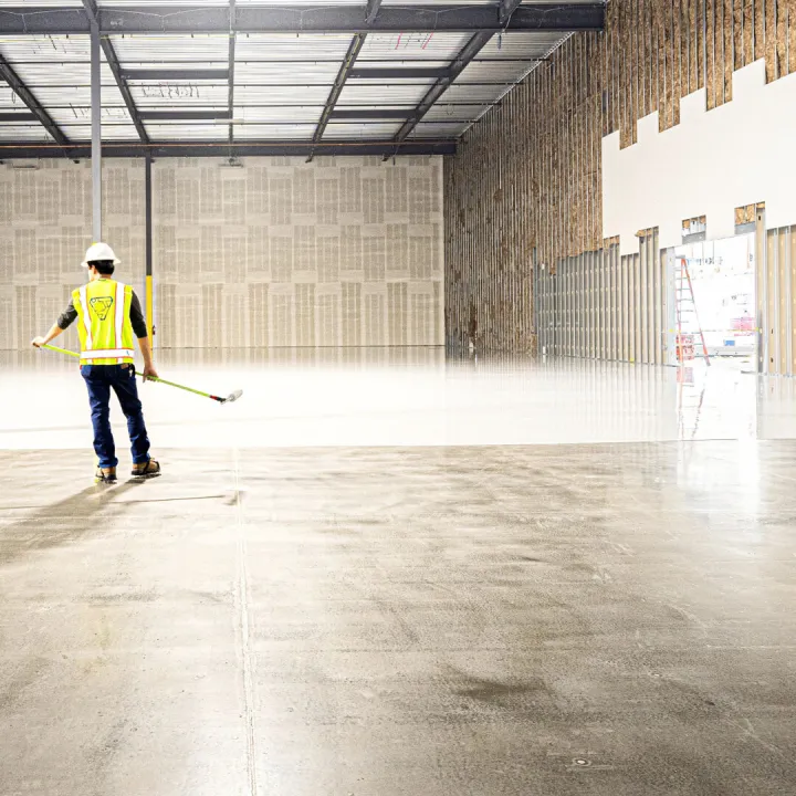 Worker in hi-vis jacket sweeping a warehouse floor