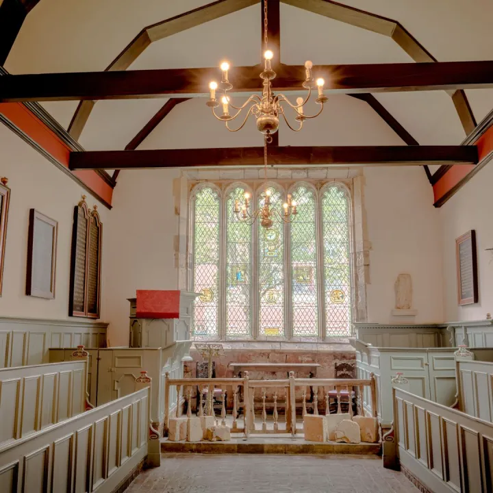 A warm chapel interior with red beams and a stained glass window