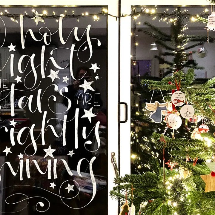 Hand painted Christmas window lettering reading Holy night all is bright