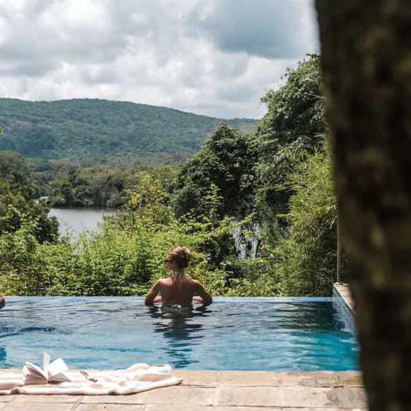 Two guests in the infinity pool looking out over the lake at Peacock Hill Sigiriya