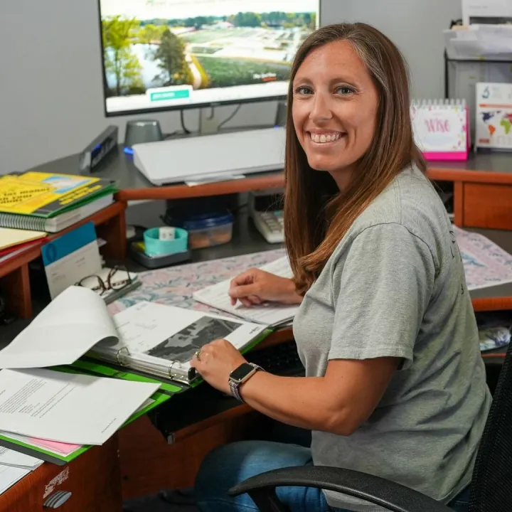 Smiling nursery manager reviewing a policy folder at an office desk