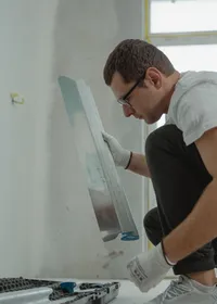 Plasterer using a metal trowel on an interior wall