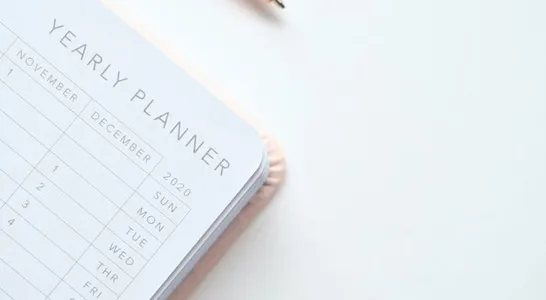 Close-Up Photo of Yearly Planner Beside a Pen 