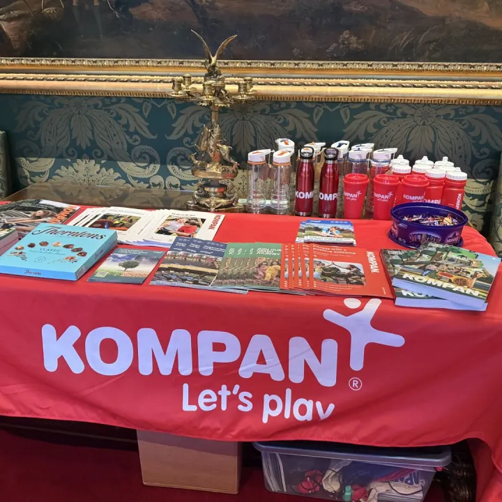 Kompan exhibition stand with brochures on a red table cover