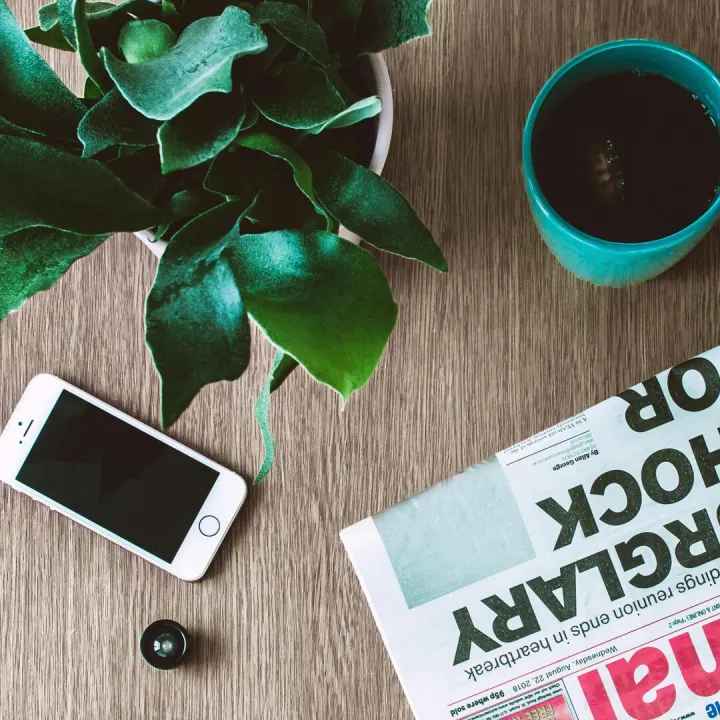 Flat lay arrangement of a coffee mug, newspaper