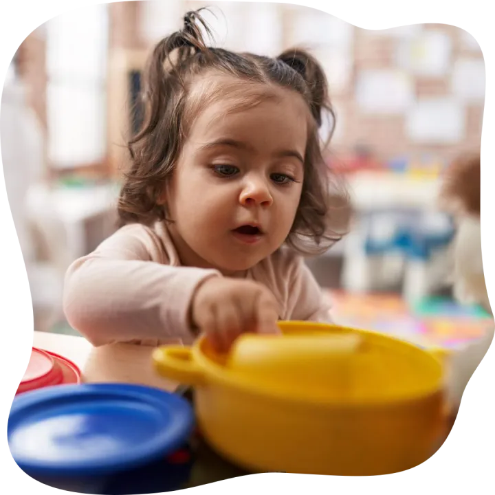 Adorable hispanic girl playing with play kitchen standing at