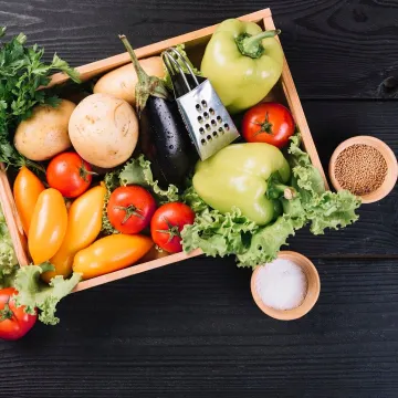 Fresh vegetables in container and spices on black