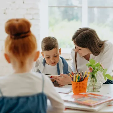 Engaging learning experience with a teacher and child exploring books and creativity in a bright classroom.
