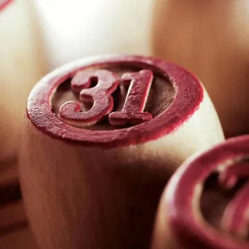 Wooden bingo game chips in focus, displaying numbers 31 and 73.