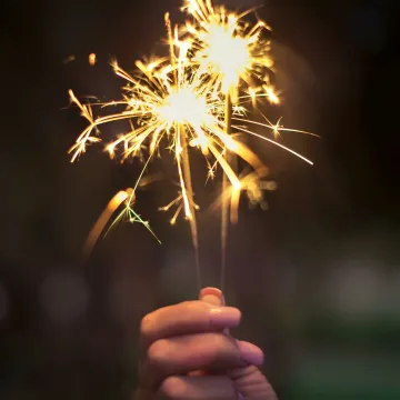 A hand holding sparklers glowing brightly in a dark night, capturing the essence of celebration.