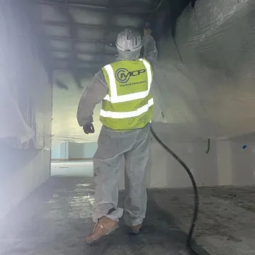 Construction worker wearing hi-vis jacket spraying surface