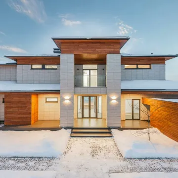 Backyard view of new modern luxurious cottage house with stone and wooden facade and illumination in winter countryside