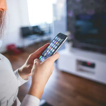 Woman browsing smartphone indoors, highlighting modern technology and communication in a cozy home setting.