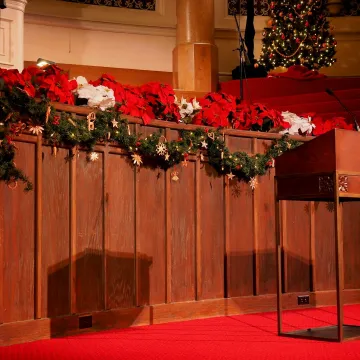 Beautifully decorated church interior featuring festive Christmas garlands and red poinsettias.