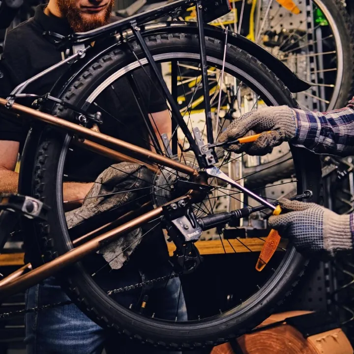 Red head bearded mechanic fixing rear derailleur from a bicy