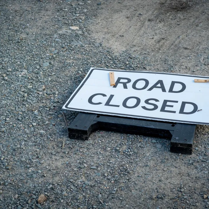 A road closed sign lies on a gravel pathway